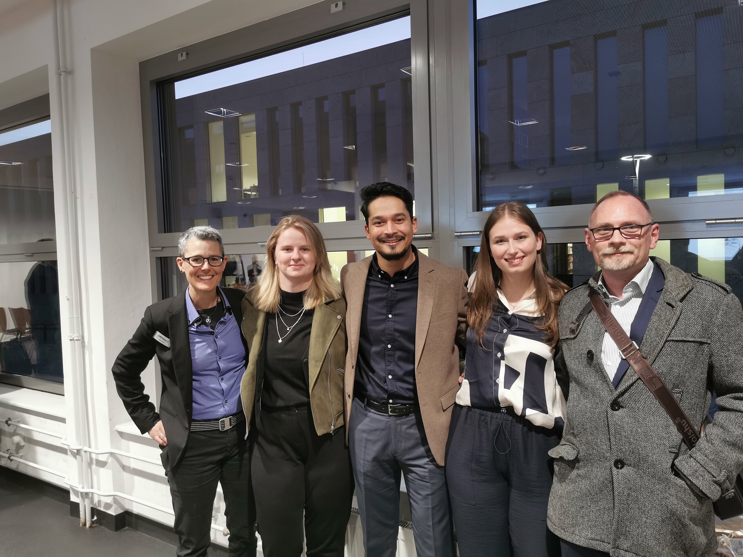 Abbildung fünf Personen vor einem Fenster