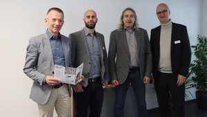 Abbildung vier Personen vor einer weißen Wand