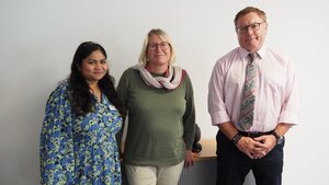 Zwei Frauen und ein Mann stehen vor einer Wand